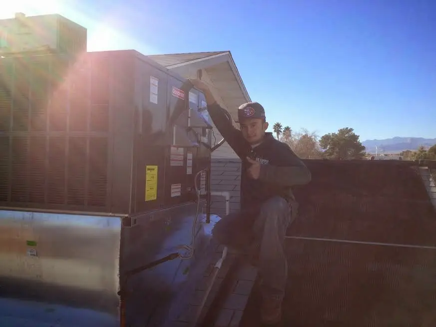 HVAC technician performing AC Tune-Up on a rooftop unit in Manistee