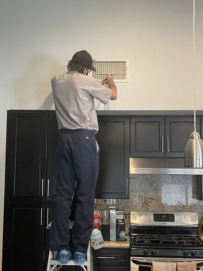 Technician inspecting an air vent during HVAC service in Manistee
